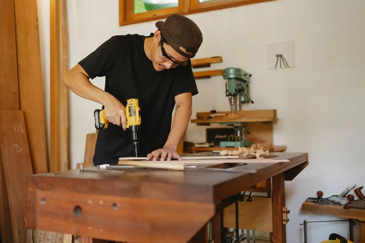 Menuisier perçant une pièce de bois à l'établi